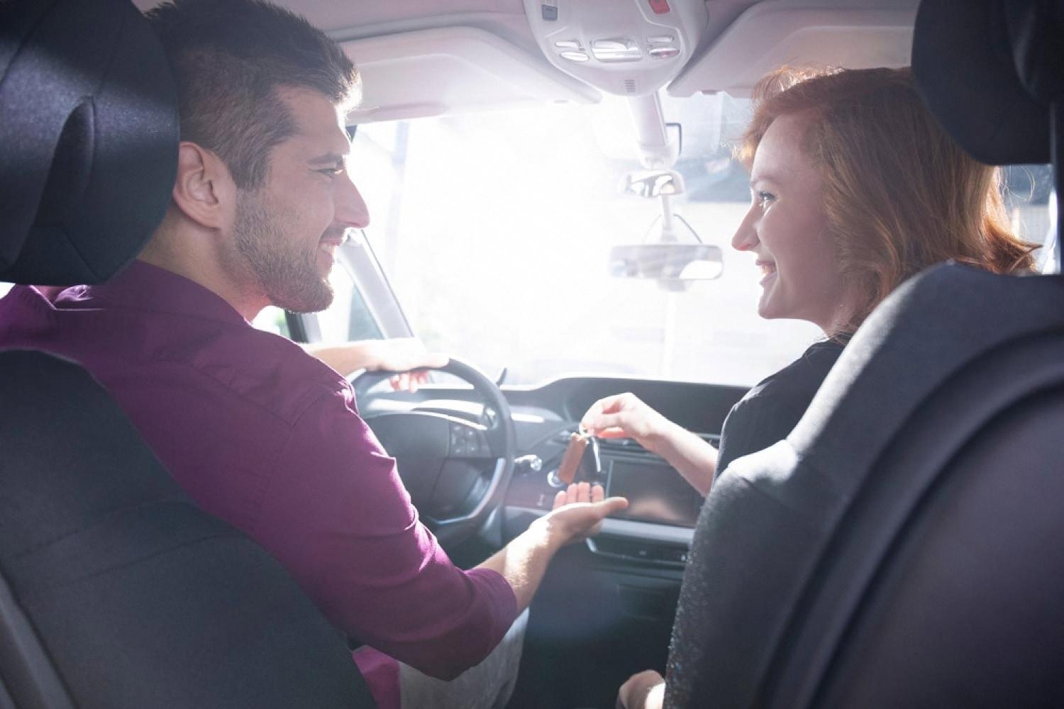 Man handing car keys to a woman inside a family vehicle