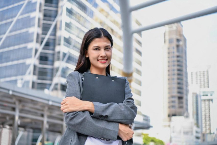 Confident female manager holding a folder in front of a Dubai office tower