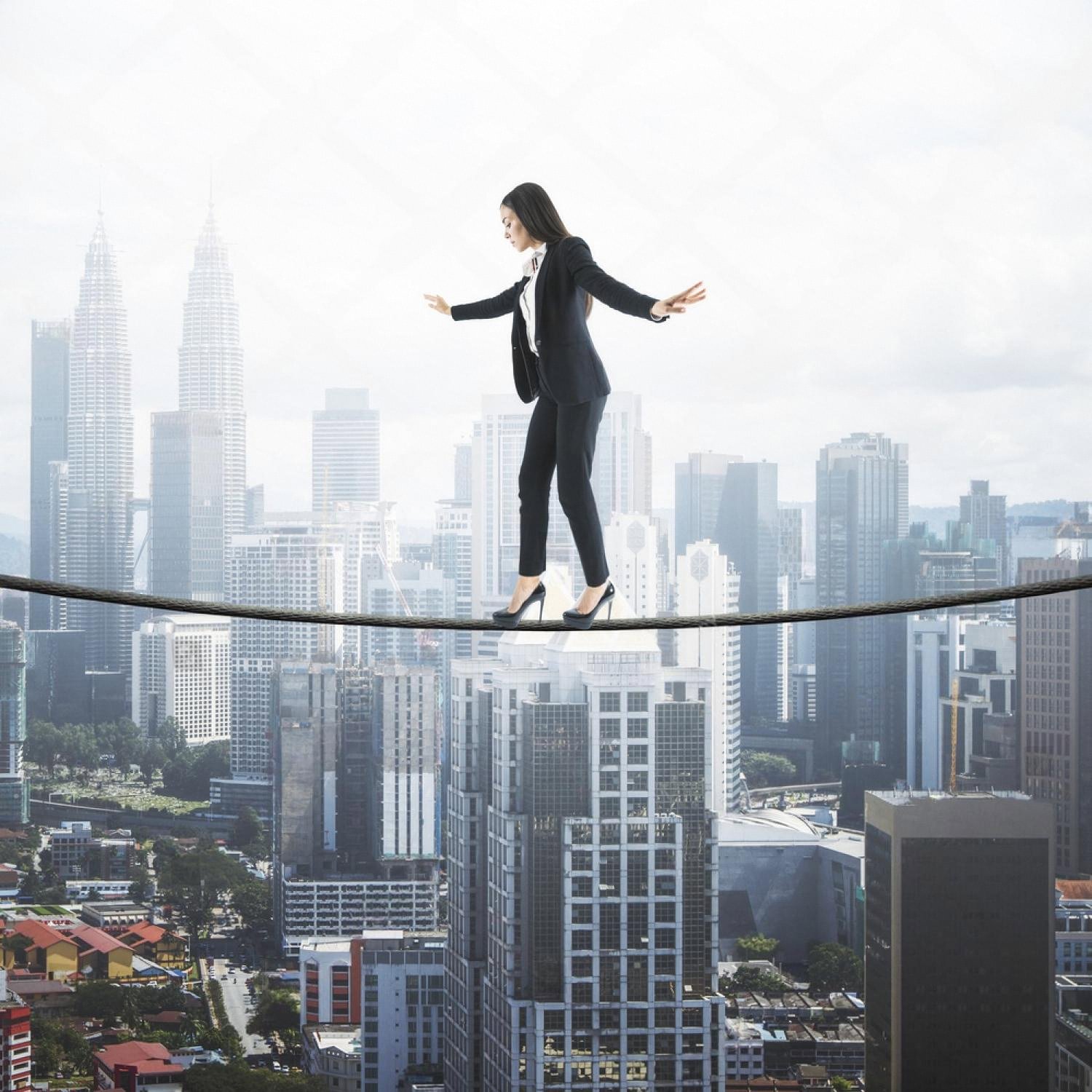 Business woman balancing on a rope above a city skyline, a metaphor for leadership resilience